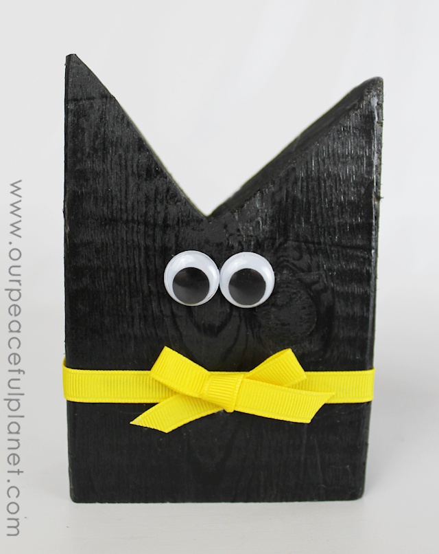 Make this simple black cat Halloween craft from 2x4 pieces, a little paint, ribbon and wiggle eyes! An inexpensive way to decorate your house for Halloween! 