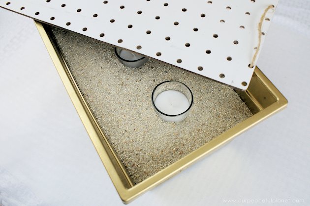 This DIY table centerpiece allows you to change decor year round for any occasion. Then lift out the pegboard insert to find candles for ambient lighting!